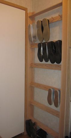 shoes are lined up on the shelves next to a closet door in a room with white walls and wood flooring