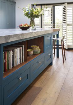 a kitchen island with bookshelves and a bowl of fruit on the counter top