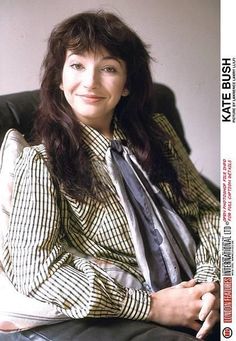 a woman sitting in a chair with her arms crossed and looking at the camera smiling