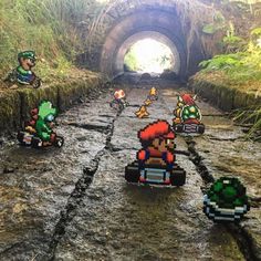 several nintendo mario kart cars driving through a tunnel in the middle of a forest