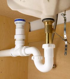 a white sink sitting under a faucet next to a wall mounted faucet