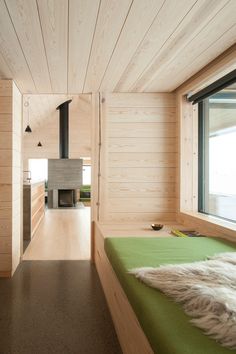 a bedroom with wood paneling and green bedding in front of a fire place