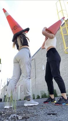 two people with hats on their heads standing in front of a brick wall and building