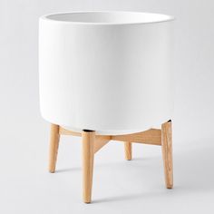 a white planter sitting on top of a wooden stand