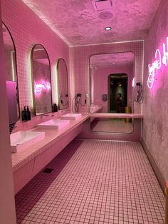 a bathroom with pink walls and tile flooring that has neon lights on the ceiling