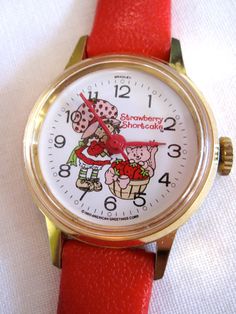 a close up of a wrist watch on a white surface with red leather straps and gold case