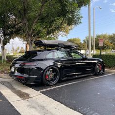 a black sports car parked in a parking lot with its surfboard on the roof