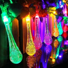 colorful lights are hanging from the ceiling in front of a wall with glass vases