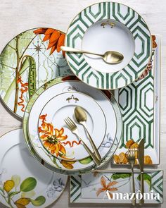 an assortment of dinnerware with flowers and leaves painted on the plates, forks and spoons