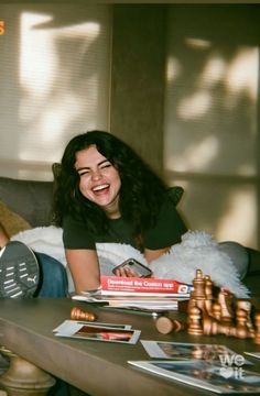 a woman laying on top of a couch next to a table filled with books and other items