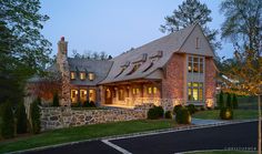 a large brick house with lots of windows and lights on it's front porch