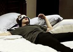 a man laying on top of a bed wearing a blindfold