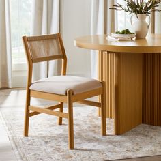 a wooden table and chair in front of a vase with flowers on top of it