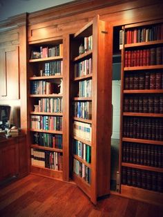 an open bookcase in the corner of a room with wooden floors and cabinets full of books