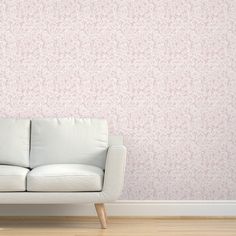 a white couch sitting in front of a pink wallpapered with small leaves on it