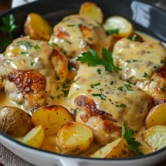 a pan filled with chicken and potatoes covered in gravy, garnished with parsley