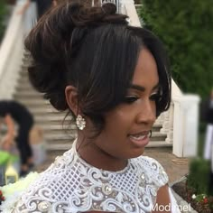 a woman with black hair wearing a white dress in front of some stairs and people