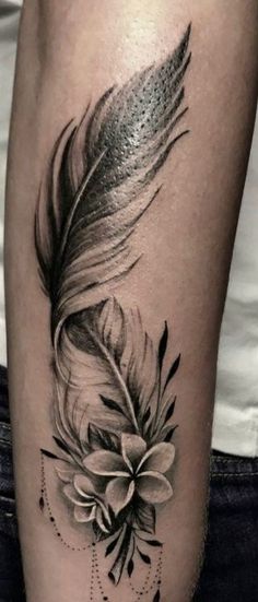 a black and white photo of a feather with a flower on the side of a woman's leg