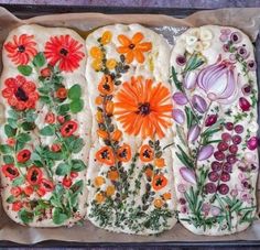 four different types of bread with flowers and herbs on them in a baking pan, ready to be baked