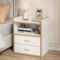 a nightstand with two drawers and a lamp on top of it next to a bed