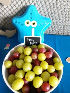 a bowl filled with grapes next to a blue star shaped sign that says fish eats