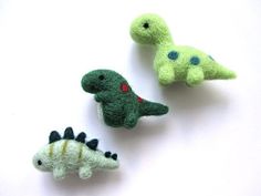 three small stuffed dinosaurs sitting next to each other