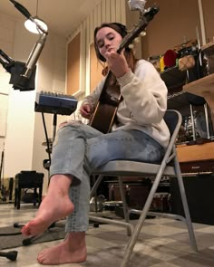 a woman sitting in a chair with her foot up and holding a guitar to her mouth