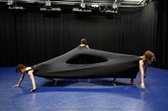 two women are bending over an upside down black object