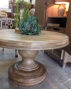 a large wooden table sitting on top of a floor next to a vase with flowers