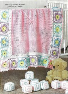 a teddy bear sitting next to blocks of crochet and a blanket with flowers on it