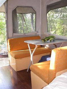 the inside of a camper with two couches and a small table in it