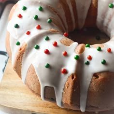 a bundt cake with white icing and sprinkles on it sitting on a cutting board