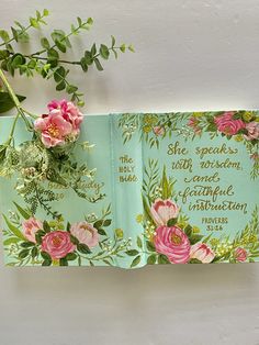 an open book with pink flowers and green leaves