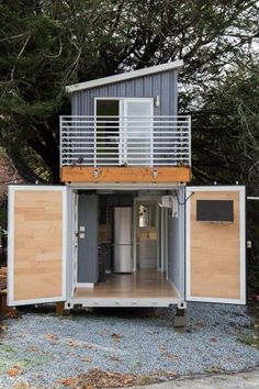 a house made out of shipping containers with a balcony on the top and doors open