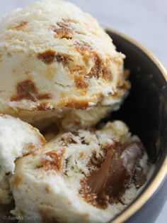 two scoops of ice cream in a bowl with caramel and chocolate chunks on top