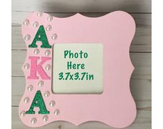 a pink frame with green letters and pearls