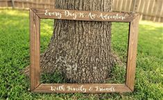 a wooden frame that says every day is my adventure with family and friends next to a tree