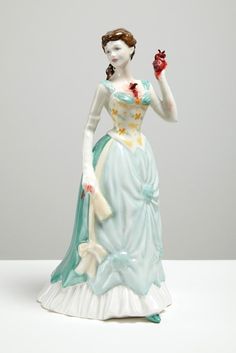 a figurine of a woman holding an apple in one hand and wearing a blue dress