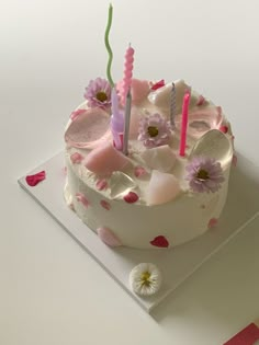 a white cake with pink flowers and candles