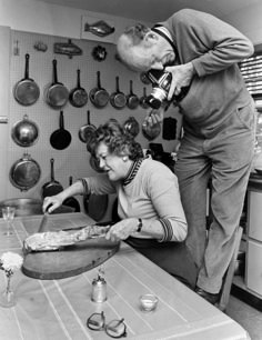 an old man is pouring something into a woman's head as she sits at a kitchen table