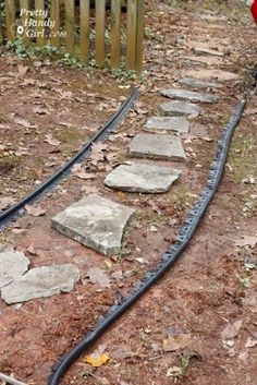 there is a train track in the middle of the yard with rocks on it and a red fire hydrant nearby