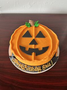 a pumpkin shaped birthday cake sitting on top of a wooden table