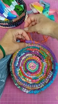 two people are working on a colorful piece of art that is being made out of yarn