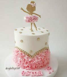 a white cake with pink ruffles and a gold figure topper on it