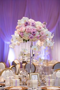 a tall centerpiece with white and pink flowers on top of a dining room table