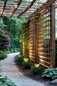 a wooden pergoline in the middle of a garden with lots of greenery