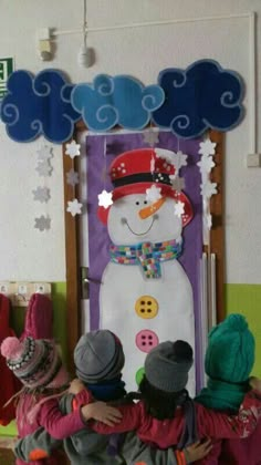 three children are standing in front of a snowman door decoration with buttons on it