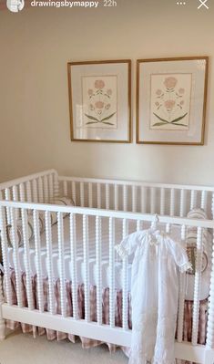 a white crib with two pictures on the wall