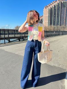 a woman is standing on the street with her hand in her hair and holding a purse