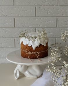 a cake with white frosting on top sitting on a plate next to some flowers